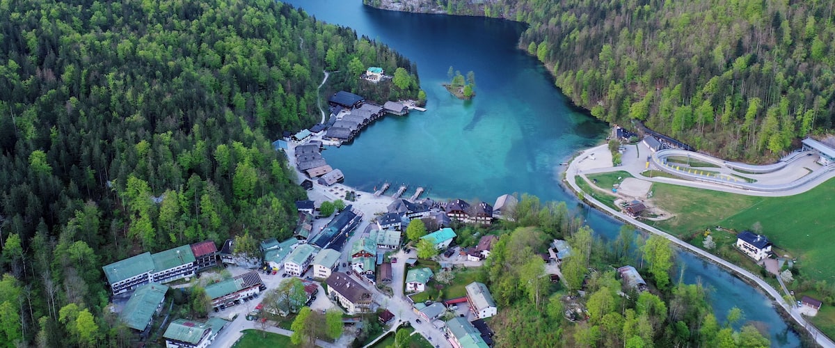 An aerial view of a lakeside village surrounded by dense forests and mountains.