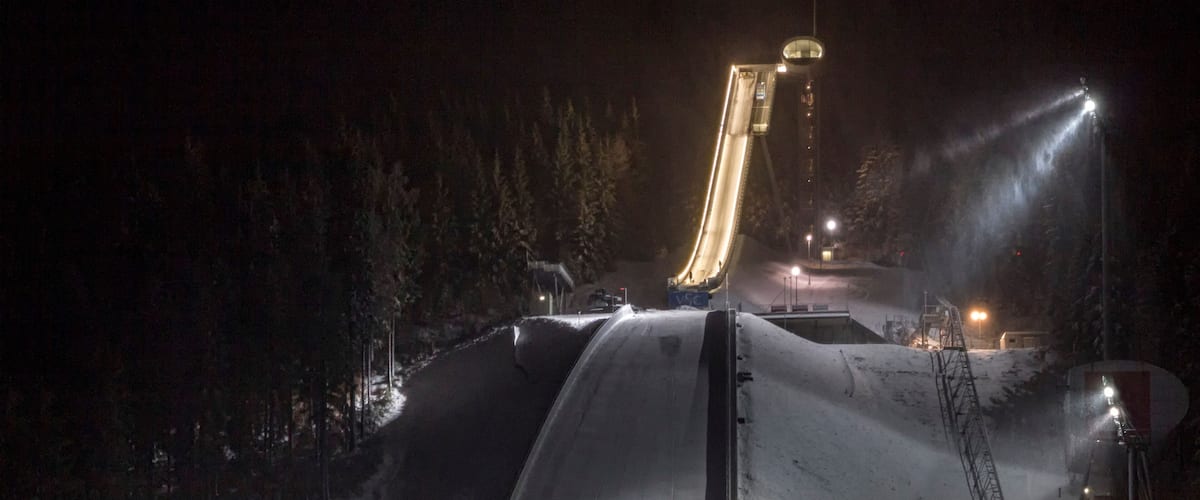 A snow-covered slope with a ski lift and artificial lighting at night.