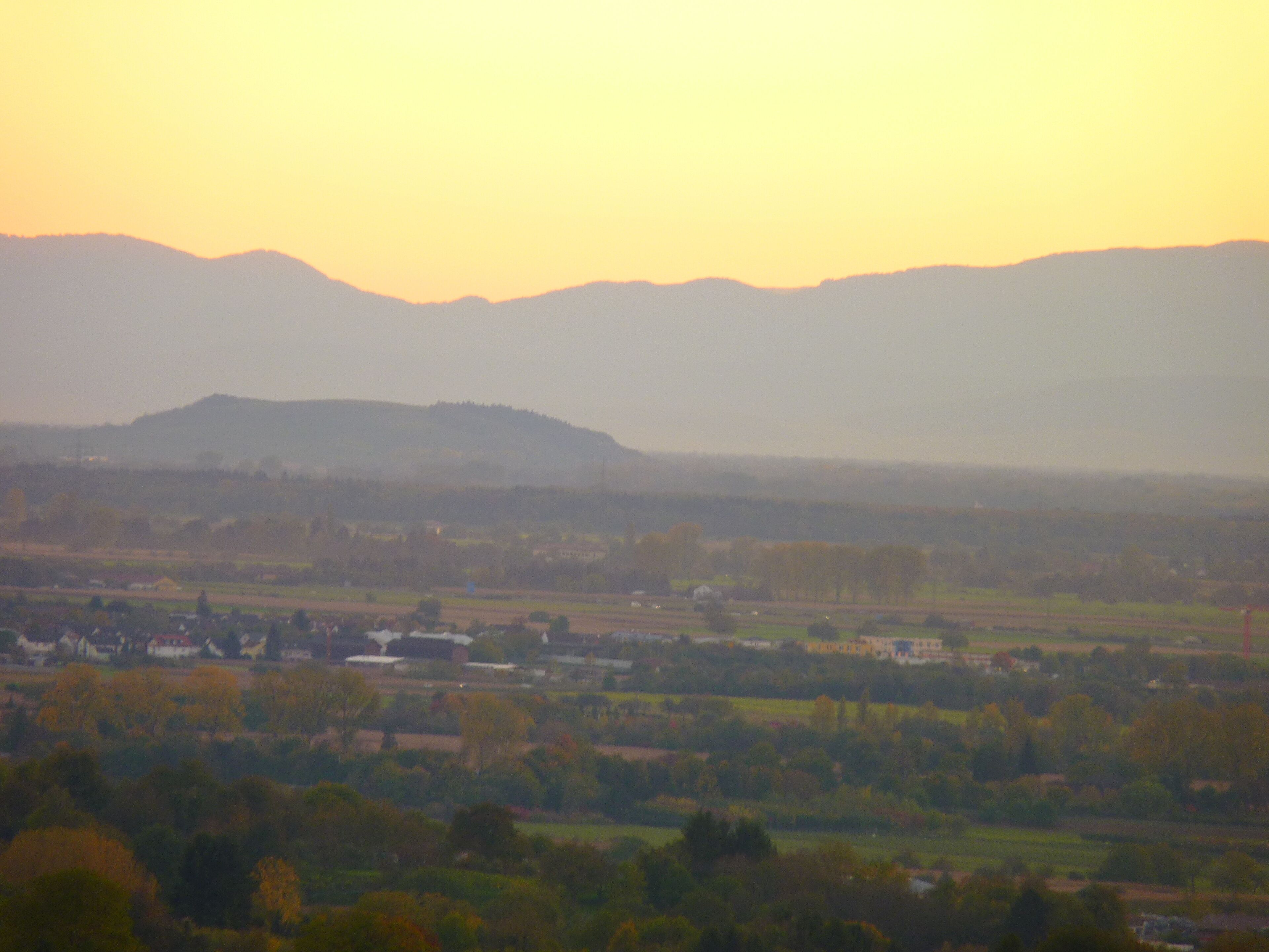 A rural landscape with rolling hills and scattered houses.