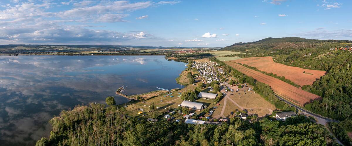 A lakeside village with boats, a dock, and surrounding fields.