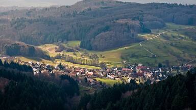 A village nestled in a valley surrounded by forested hills.