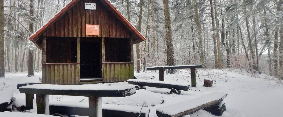 A wooden cabin named 'Himberg' in a snowy forest.