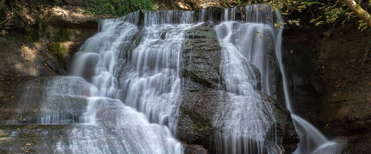 A waterfall cascading over rocks in a forested area.