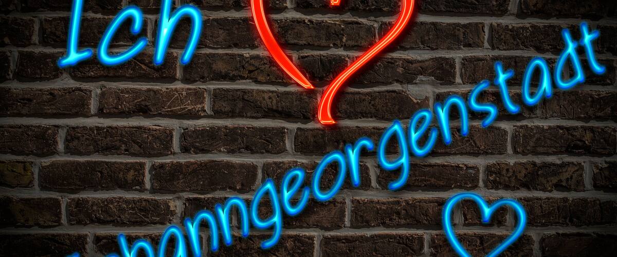 A neon sign with the text "Ich ♥ Johanngeorgenstadt" on a brick wall.