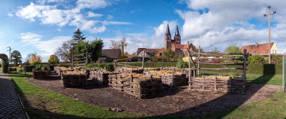 A historical site with a church, a brick tower, and a traditional wooden fence.
