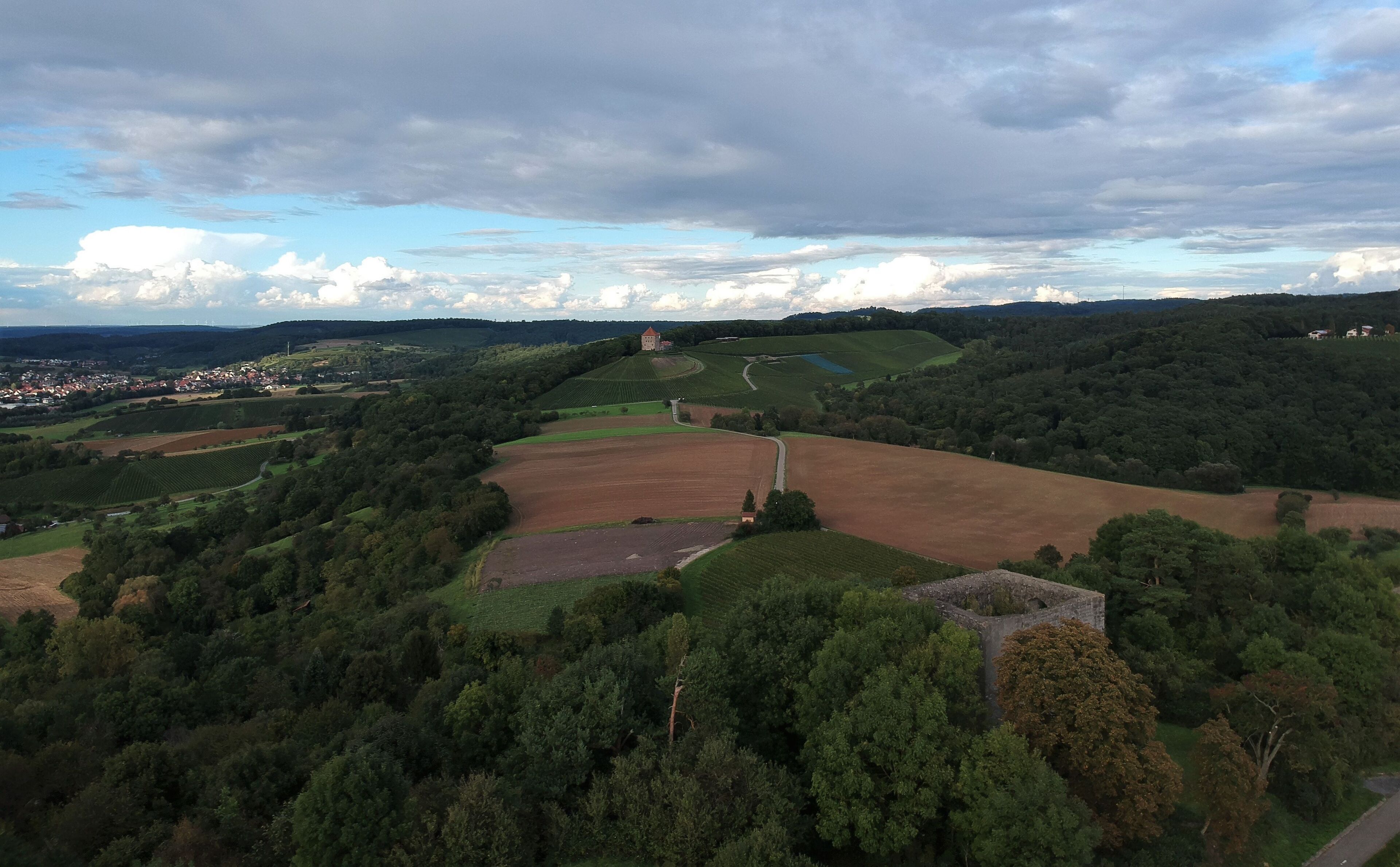 A rural landscape with fields, a castle, and a village in the distance.