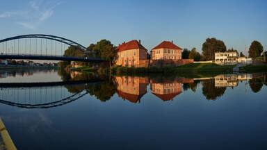 Hoya, Germany - October 10, 2021: panorama of the river Weser with the former duke's castle and the road bridge reflecting in the tranquil water during the golden hour