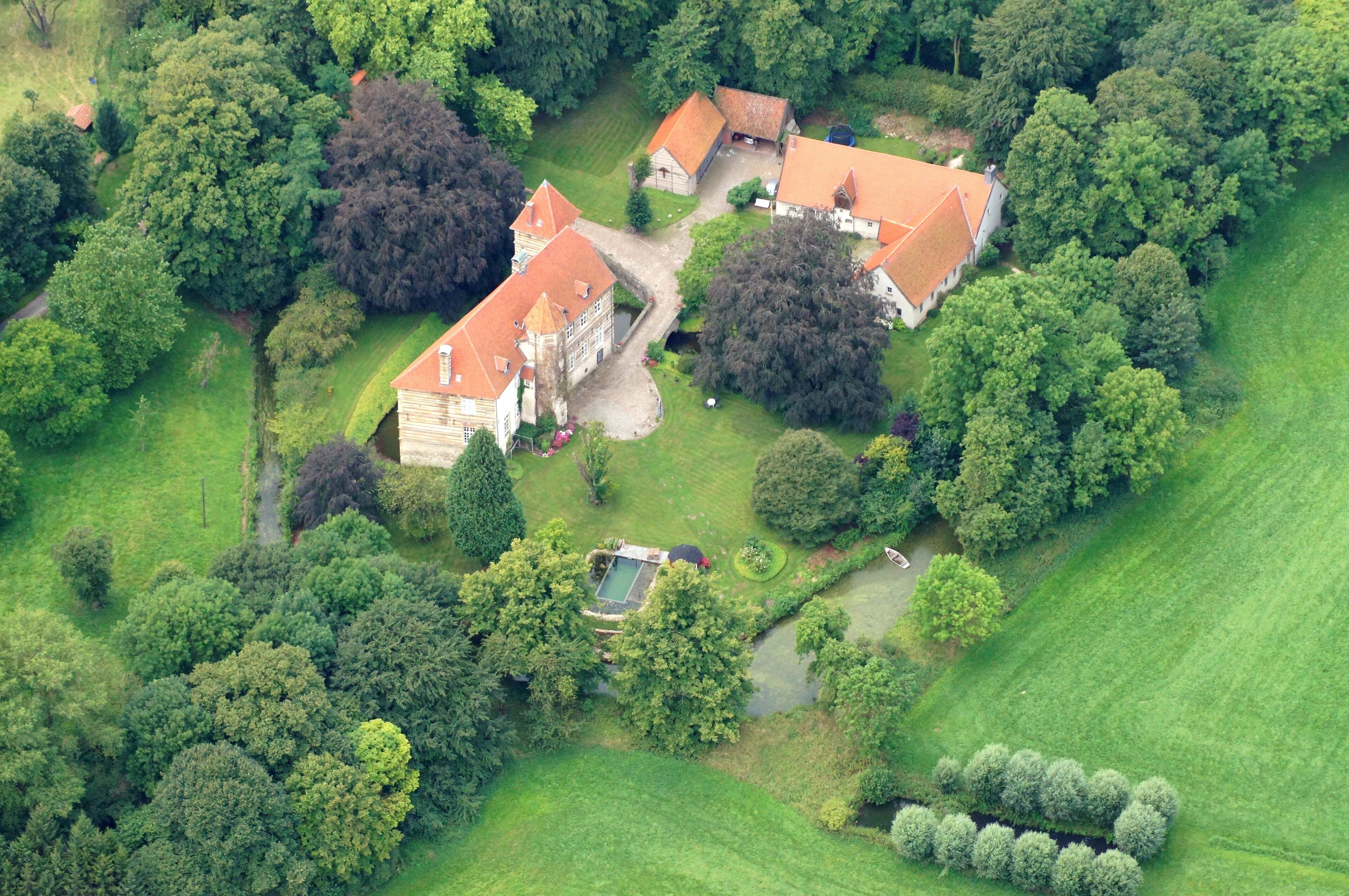 An aerial view of a large estate with multiple buildings, surrounded by lush greenery and trees.