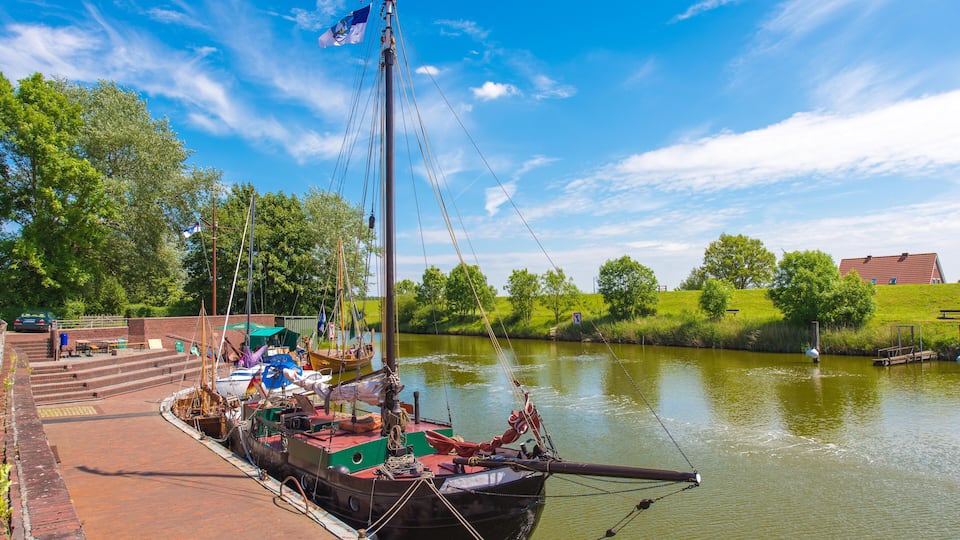 A river with a docked boat, a grassy bank, and a clear blue sky.