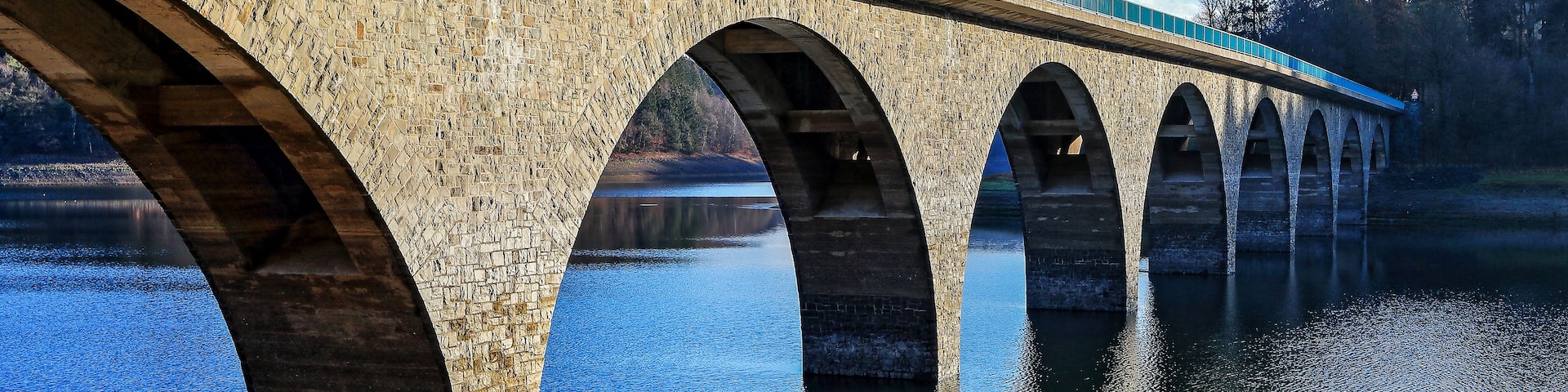 A stone bridge with multiple arches over a calm river.
