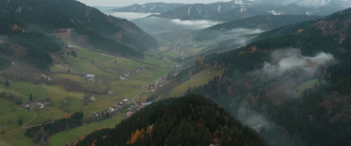 A valley with a river, surrounded by mountains and covered in mist.