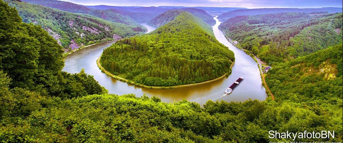 A river winding through a lush valley with dense greenery and a boat on the water.