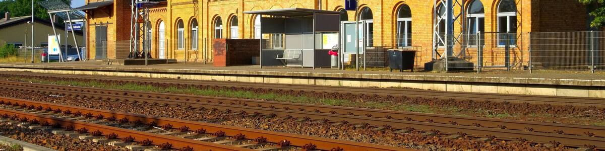 A yellow brick building with arched windows and a train station platform.