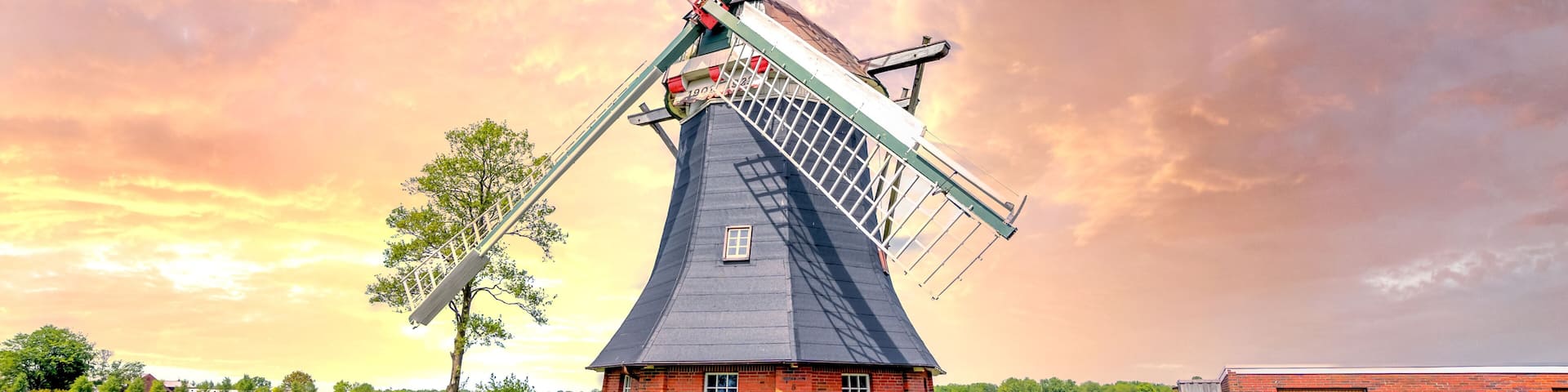 A traditional windmill with a white fence in a rural setting.