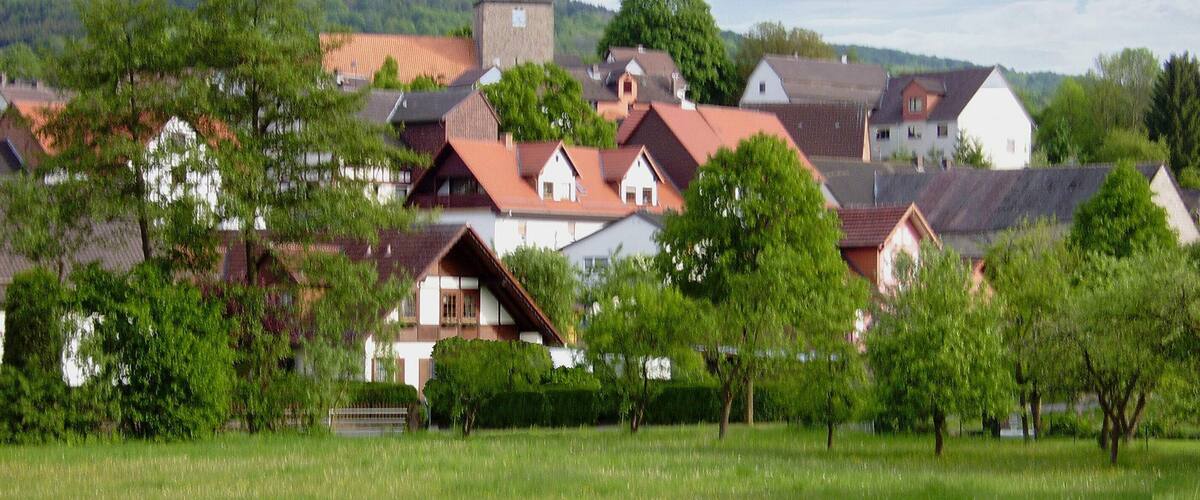 A village with traditional houses, a church, and a hill in the background.