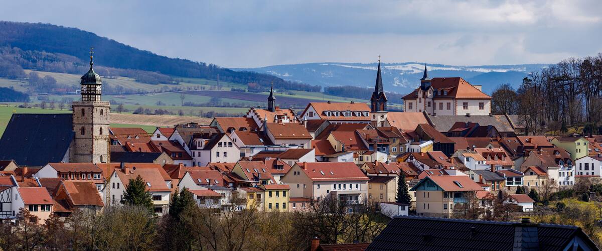 A town with red-roofed houses, a church, and a tower.
