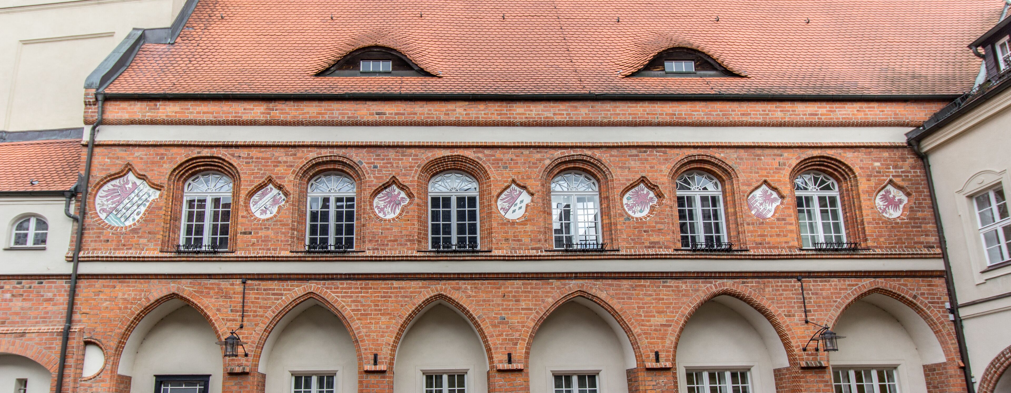 A historic building with red brick walls, arched windows, and decorative tiles.