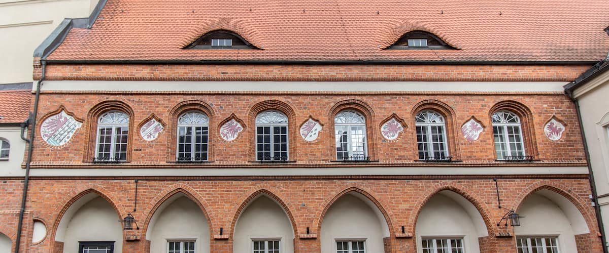 A historic building with red brick walls, arched windows, and decorative tiles.