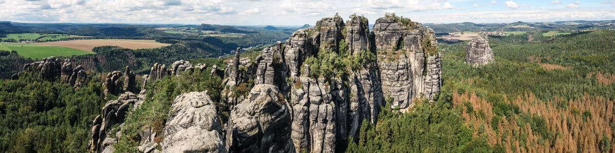 wide panorama of schrammsteine rock-formation in saxon switzerland, elbe sandstone highlands, germany with blue sky