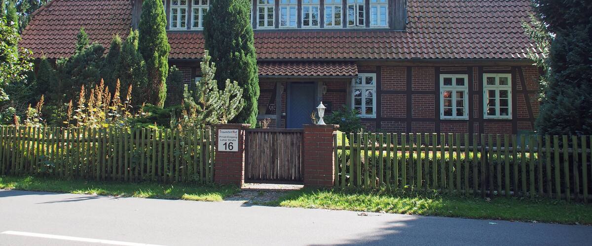 A two-story house with a tiled roof, a wooden fence, and a sign indicating it is a school.