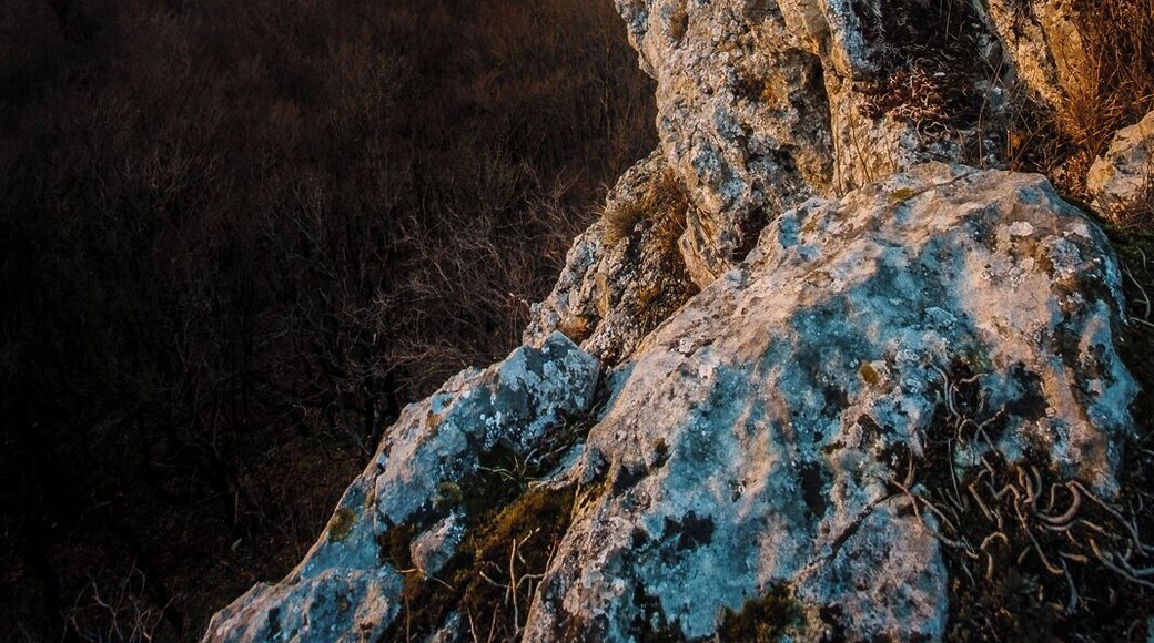 Der Mädlesfels wie er im Sonnenuntergang über Eningen und Pfullingen wacht. Im Hintergrund sieht man die Achalm zwischen den Städten und Wäldern emporragen.