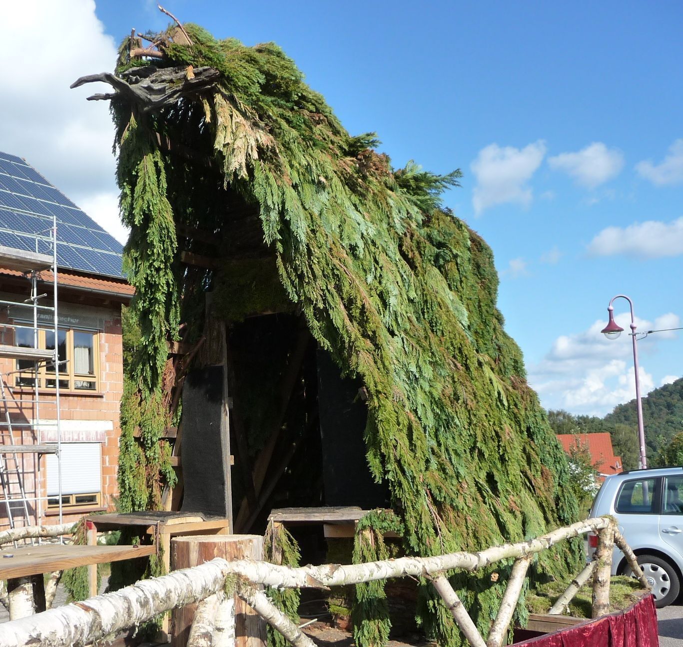 A house covered in greenery, a solar panel, and a car.