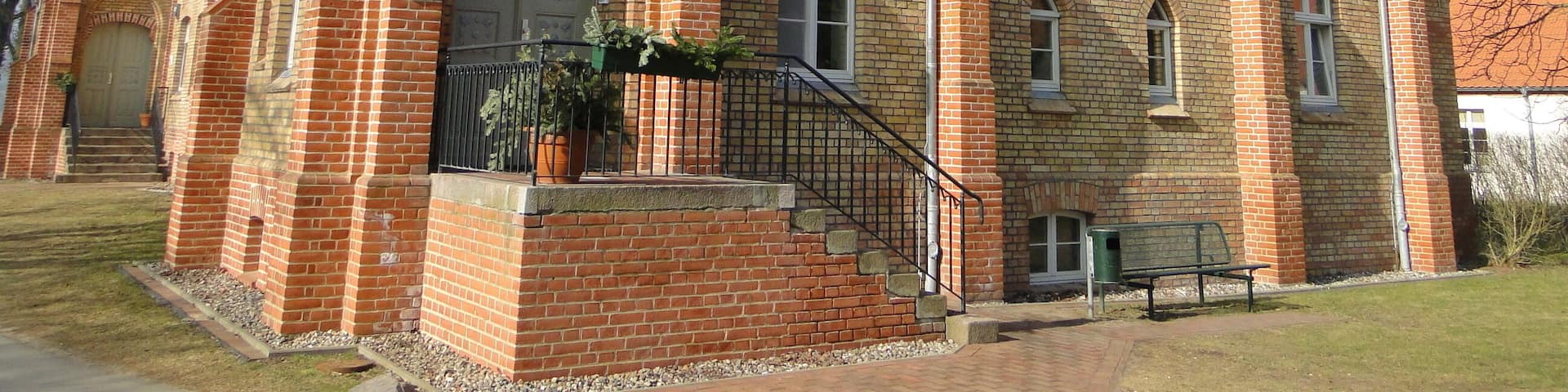 A large brick building with a balcony, a staircase, and a garden area.