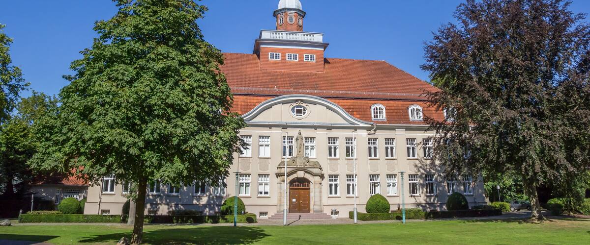 A large, historic building with a prominent tower and a red-tiled roof.