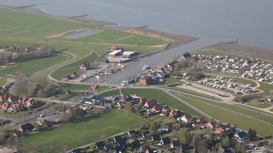 A coastal town with a marina, houses, and green fields.