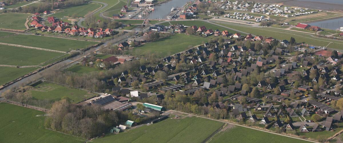 An aerial view of a coastal town with a river, green fields, and residential areas.