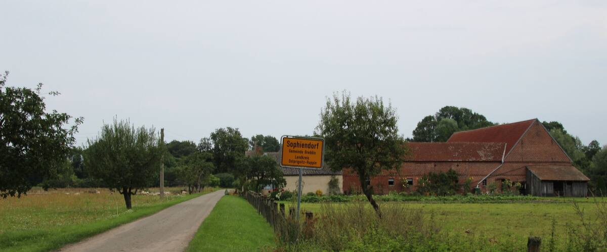 A rural road with a sign indicating 'Sophiendorf' and 'Bergheim'.