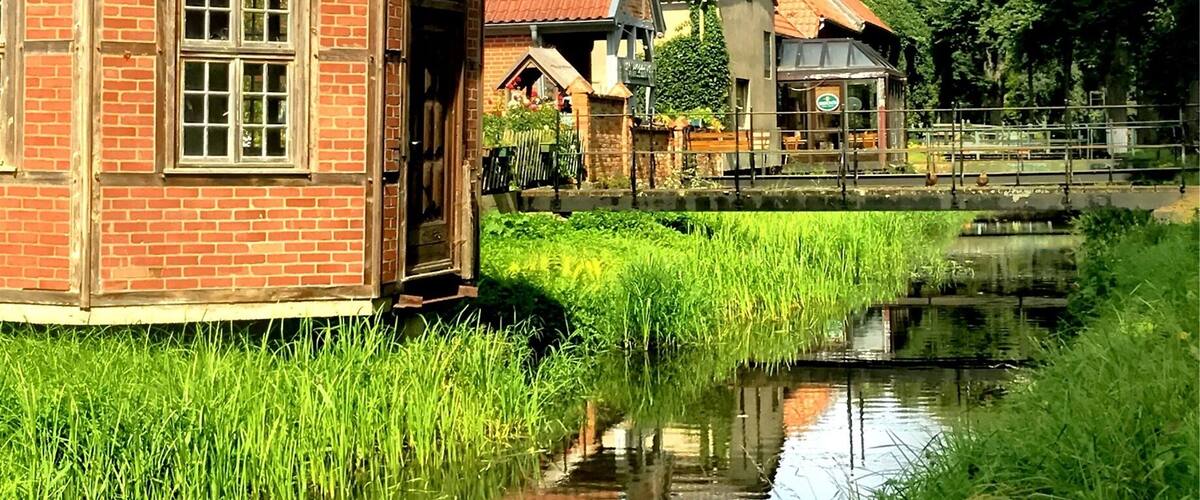 A canal with a brick building and a house with a red roof.