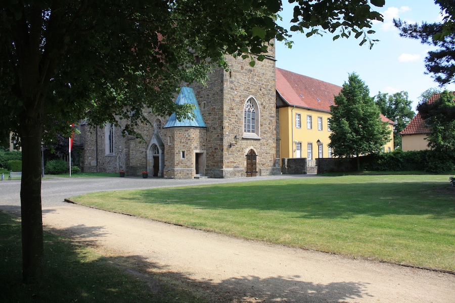 A church with a blue roof, a yellow building, and a green lawn.