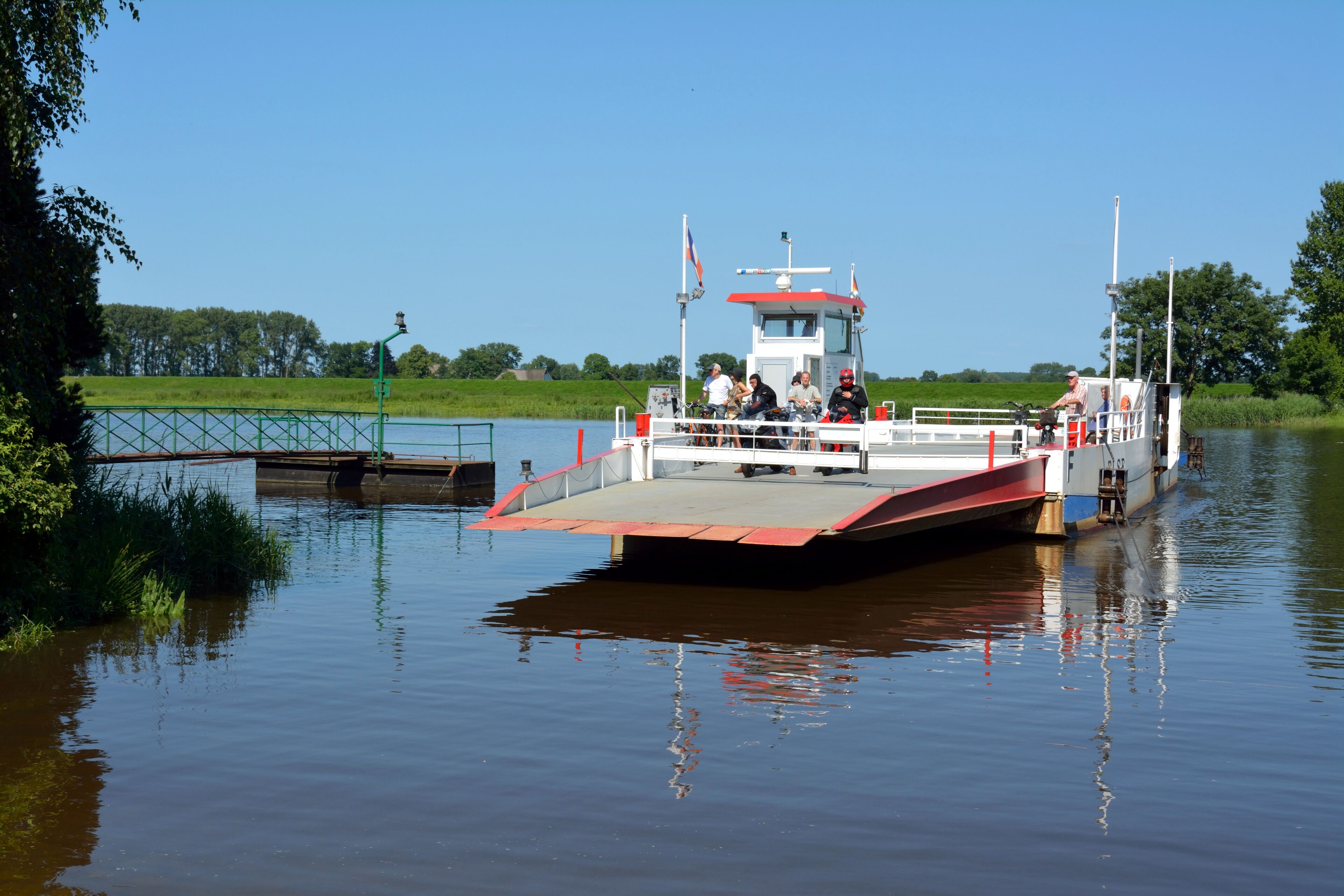 A riverboat docked at a pier with a small bridge in the background.