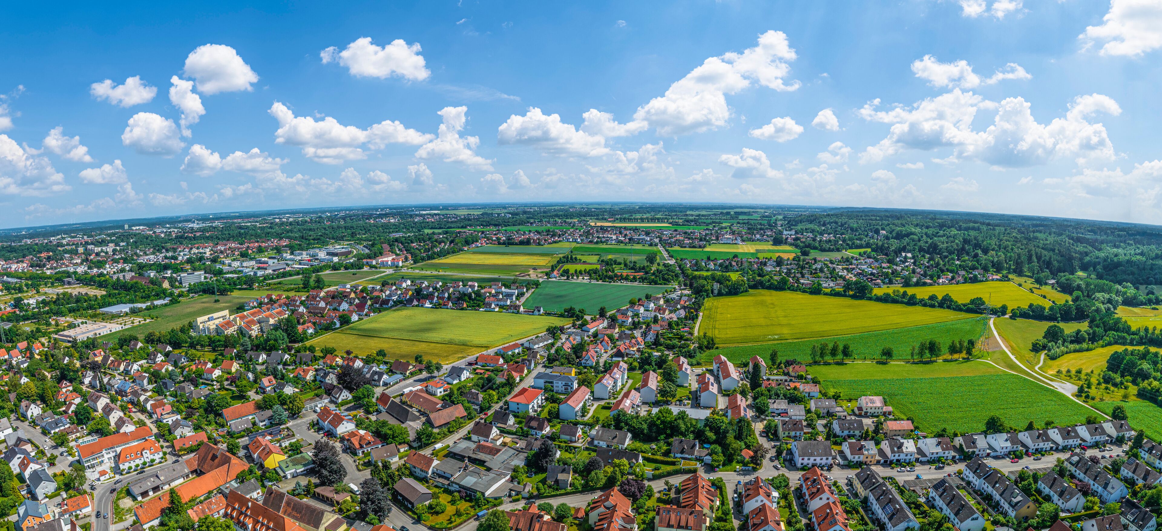 An aerial view of a town with residential areas, green fields, and scattered buildings.