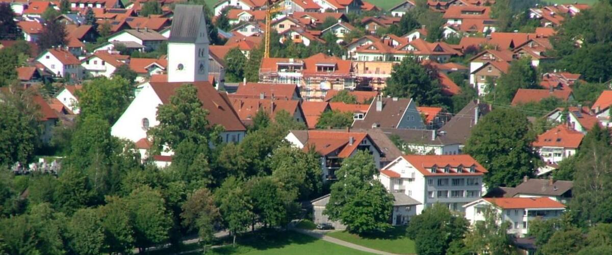 En landsby med røde tage, en kirke med et tårn og omkringliggende grønne marker.