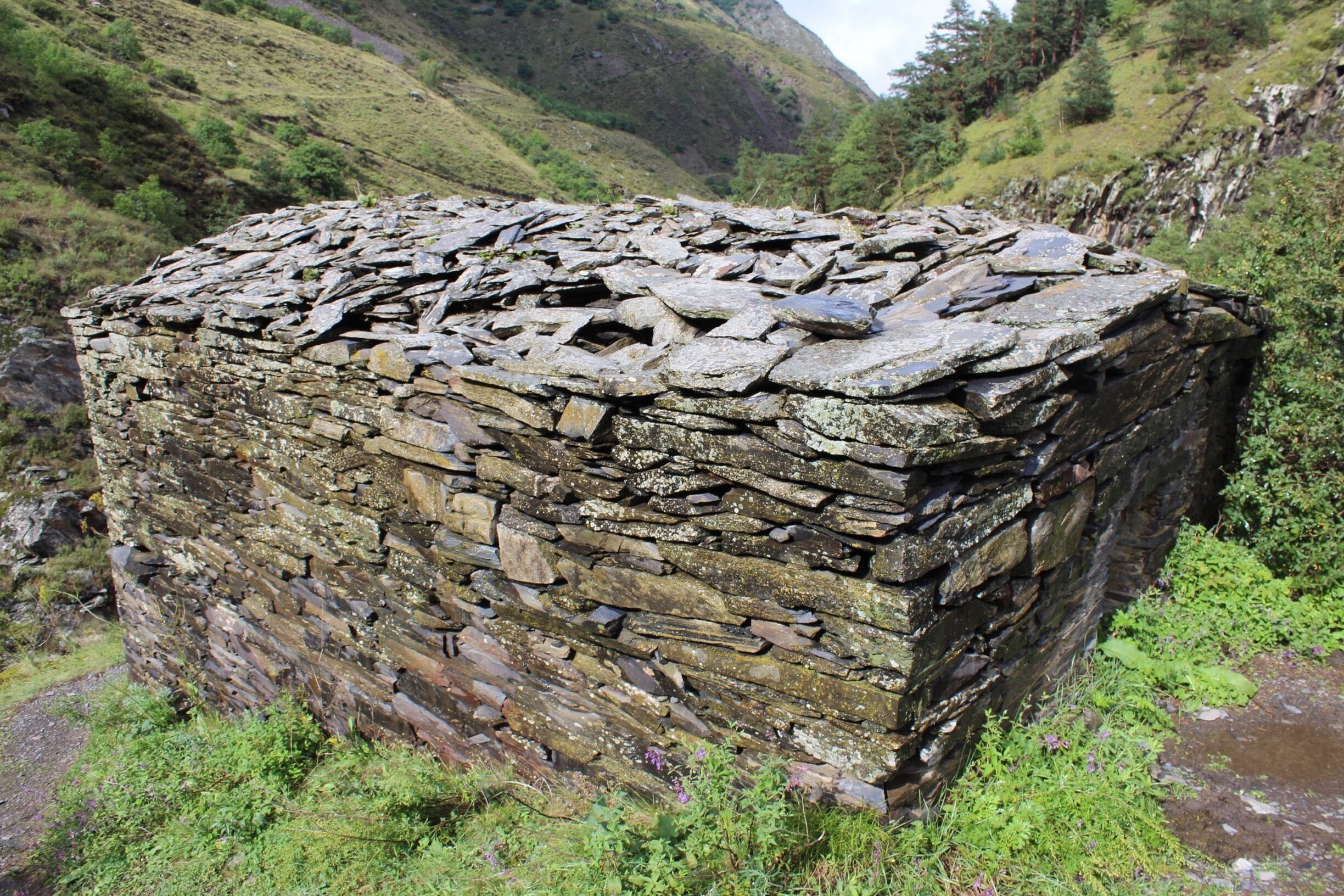 #anatori #khevsureti View of a thing called the Anatori Crypts. Located in a river canyon in the country of Georgia, close to the border with the Russian region of Chechnya.

You can look inside of these stone crypts and see large piles of human bones. The exact story of what happened here isn’t known for sure, but there apparently was a village of Anatori that disappeared long ago in some sort of plague. 