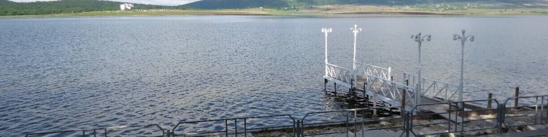 A calm lake with a dock and a pedestrian walkway.