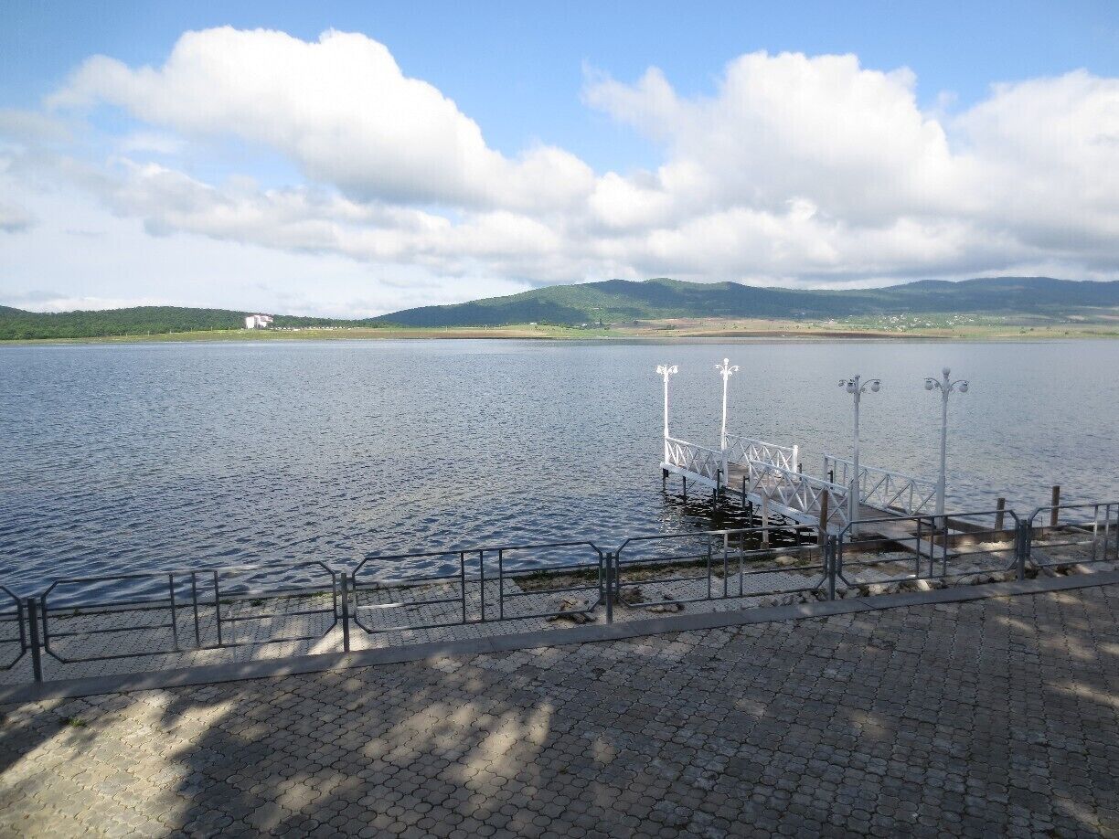 A calm lake with a dock and a pedestrian walkway.