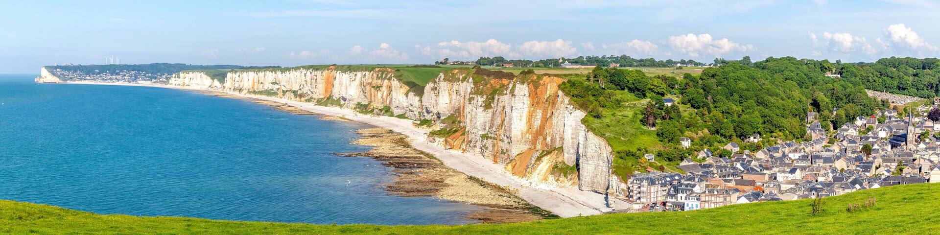 A coastal town with cliffs, a beach, and a town in the background.