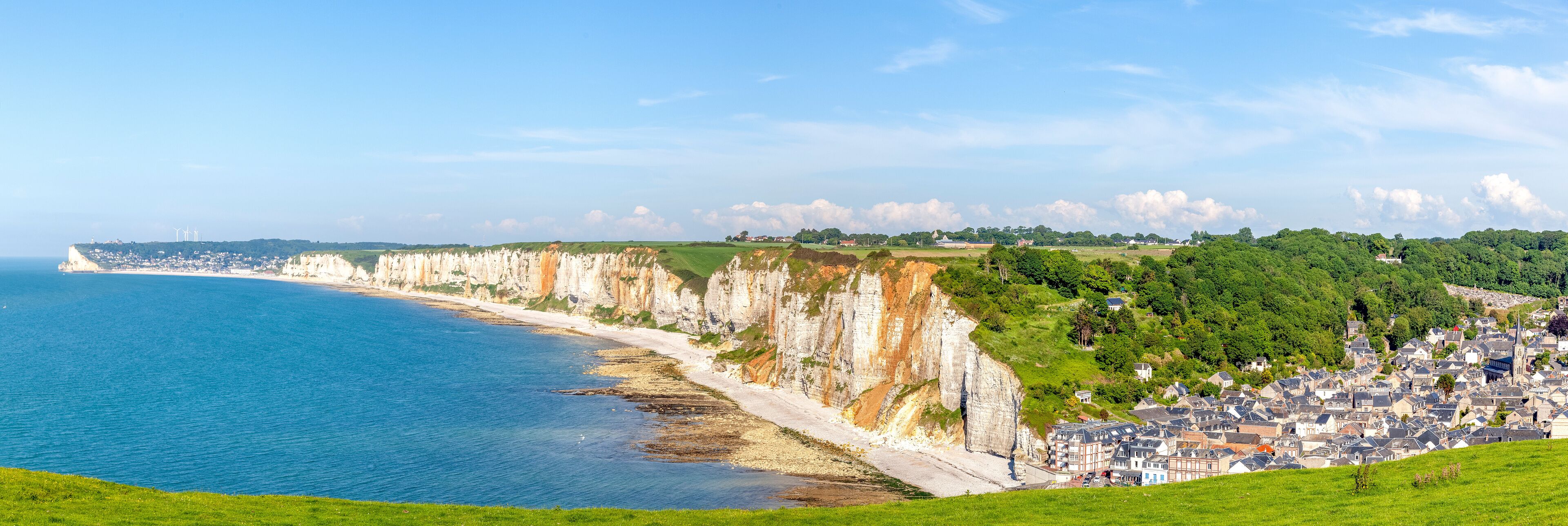 A coastal town with cliffs, a beach, and a town in the background.