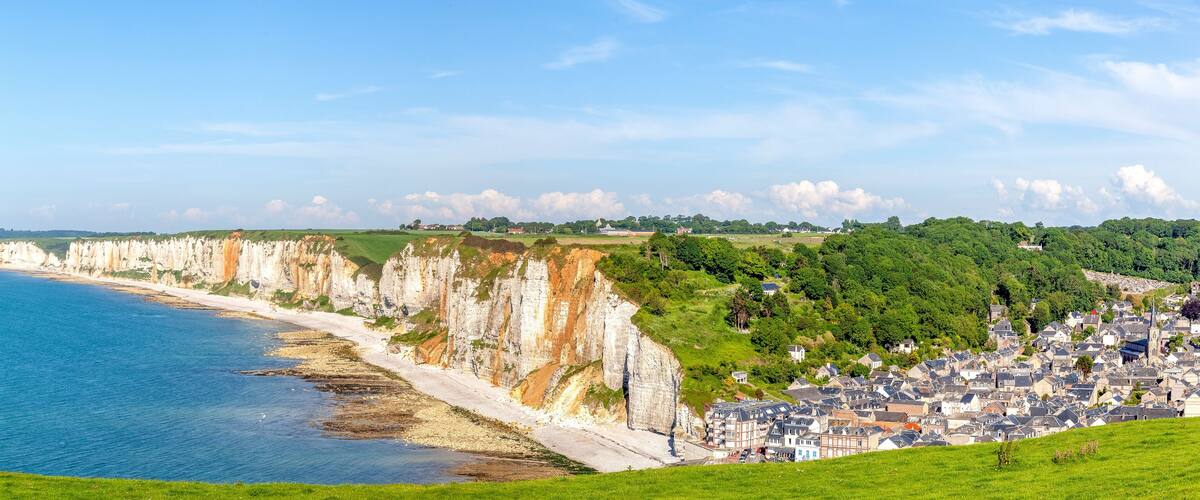 A coastal town with cliffs, a beach, and a town in the background.