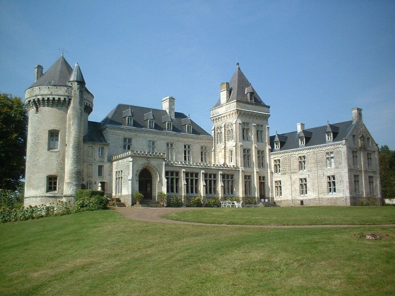 A large, historic stone building with multiple towers and a central entrance.