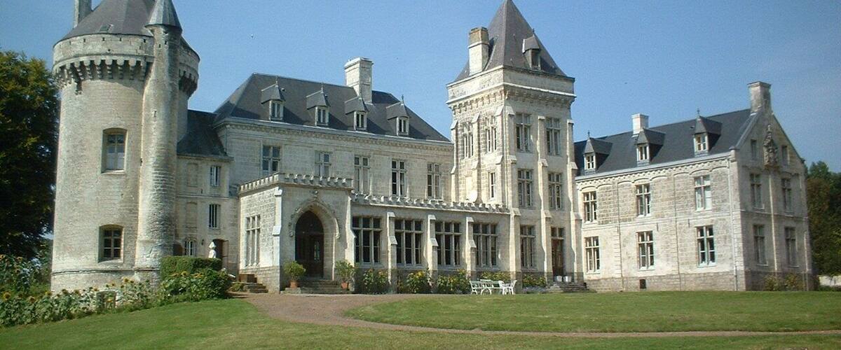 A large, historic stone building with multiple towers and a central entrance.