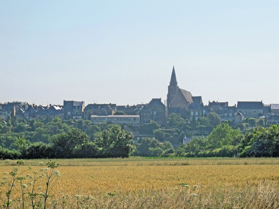 Une ville dont l’église, reconnaissable à son clocher imposant, est entourée de bâtiments résidentiels et d’un champ cultivé.