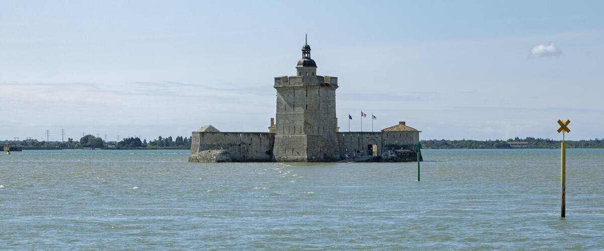 A stone lighthouse on a small island in a body of water.
