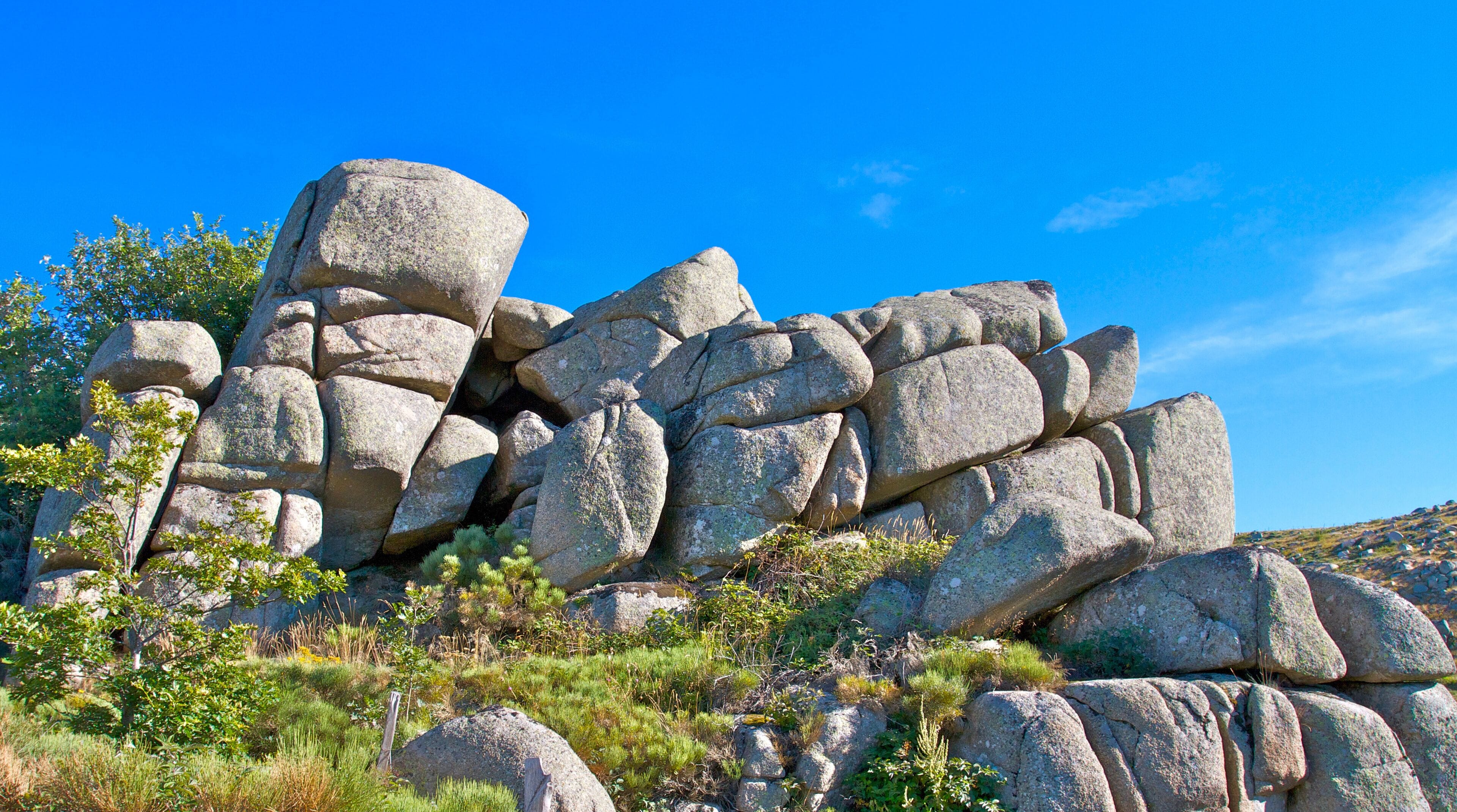A rocky landscape with large boulders and sparse vegetation.