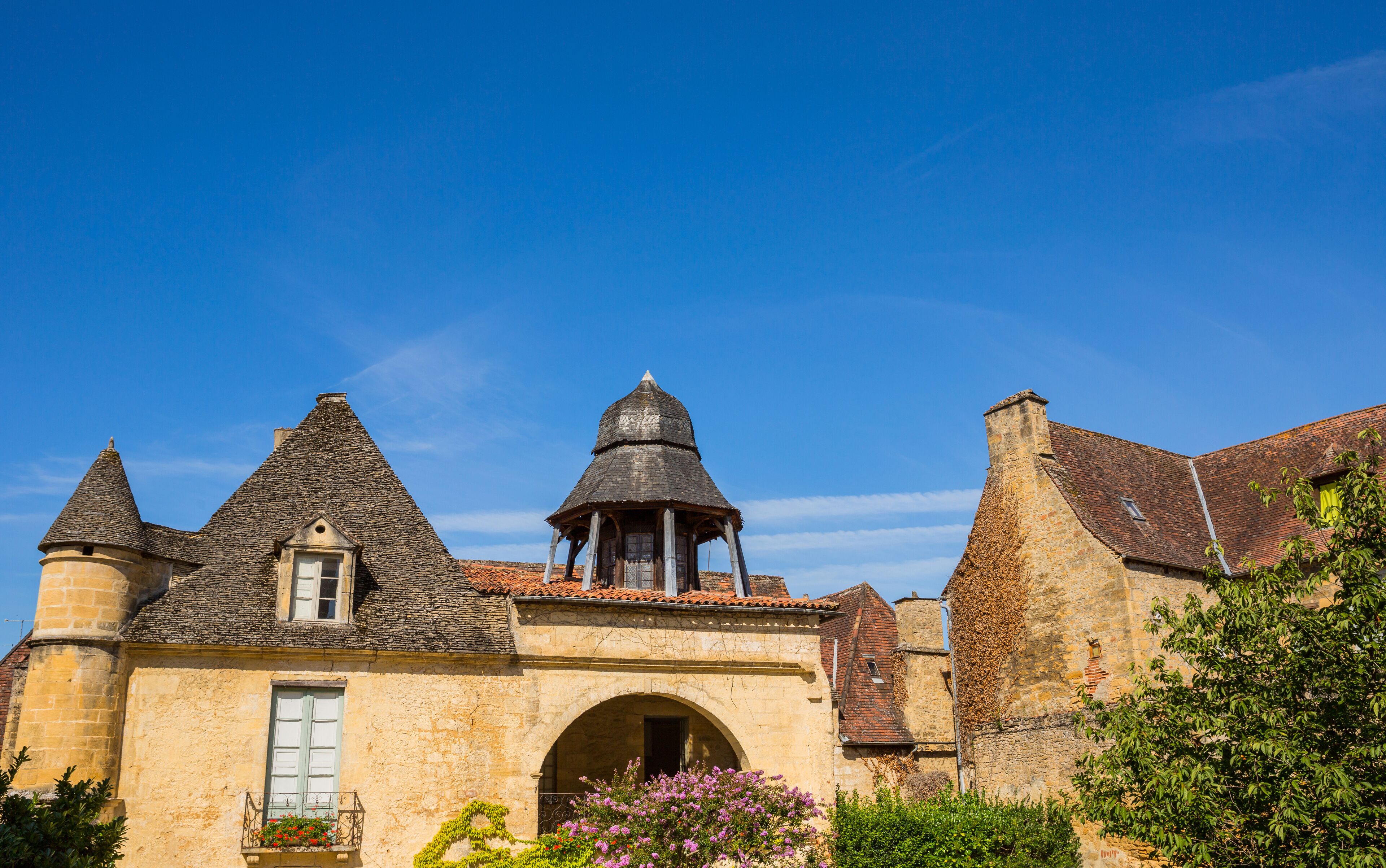A historic stone building with a tower, a bell tower, and a covered walkway.