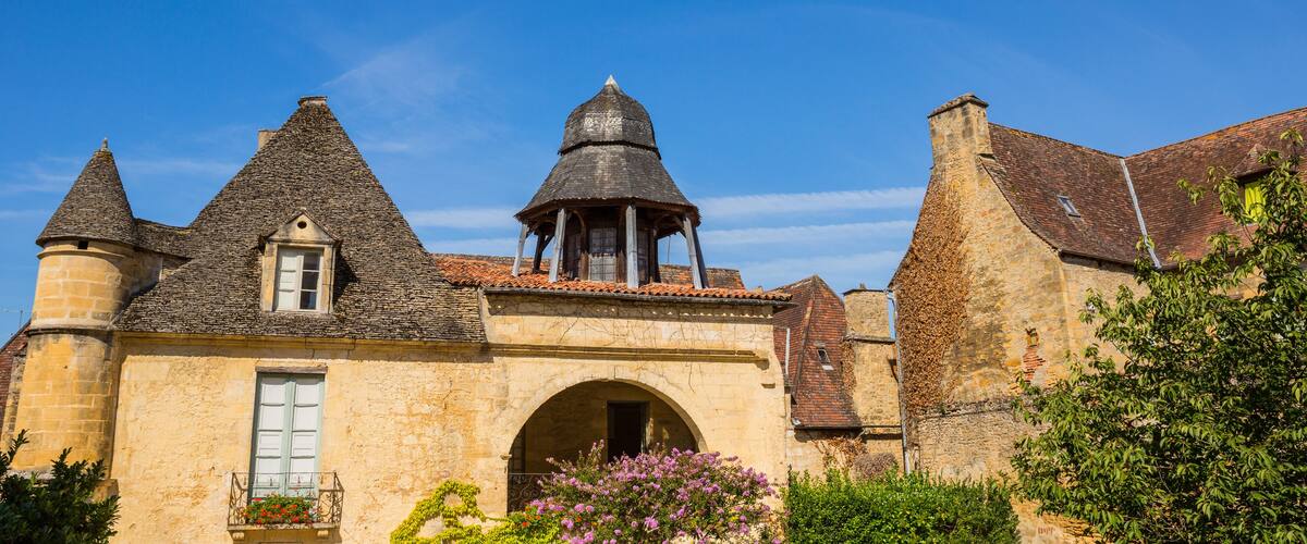 A historic stone building with a tower, a bell tower, and a covered walkway.