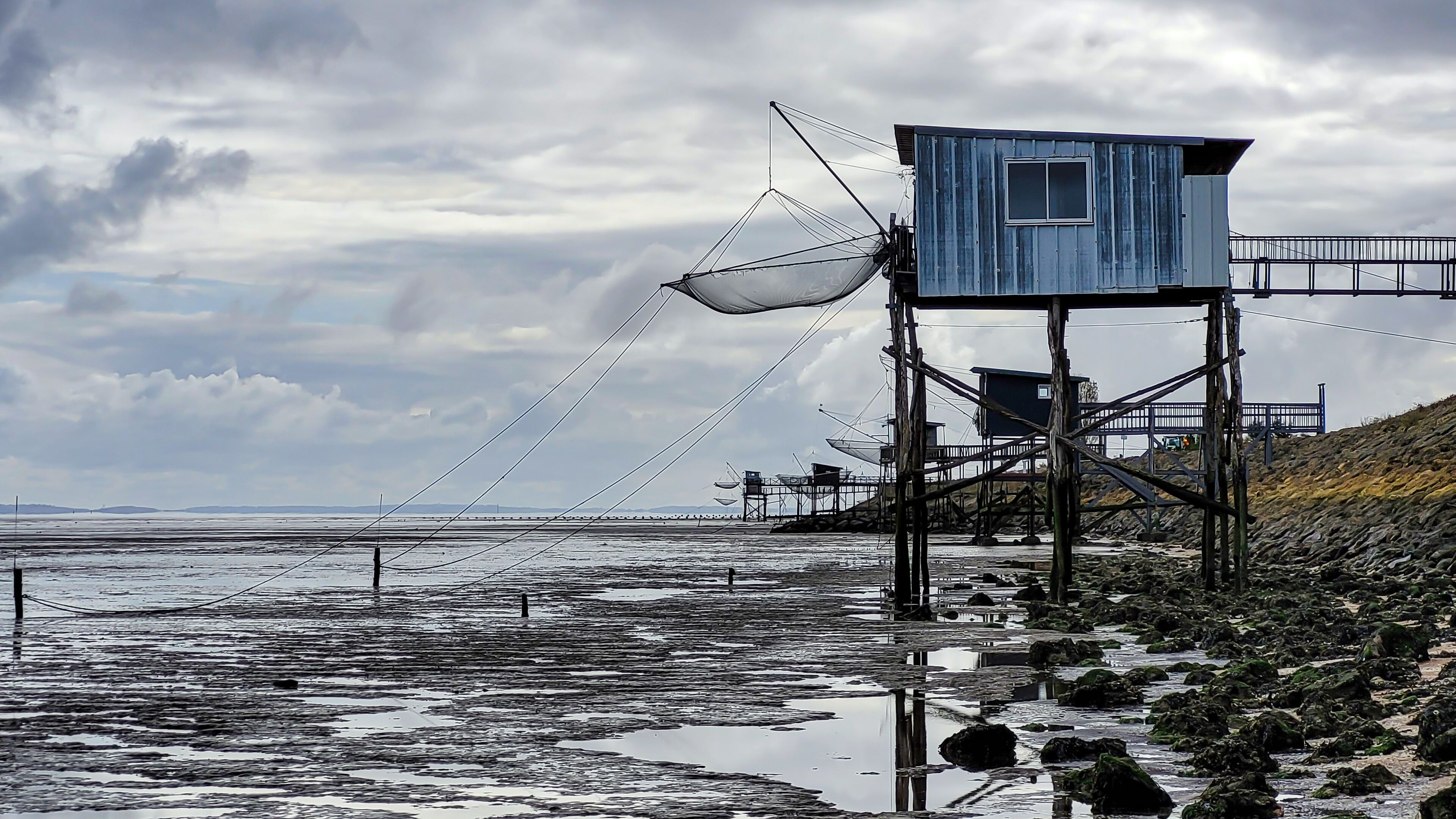 A coastal area with a blue lifeguard tower, rocky shoreline, and a cloudy sky.